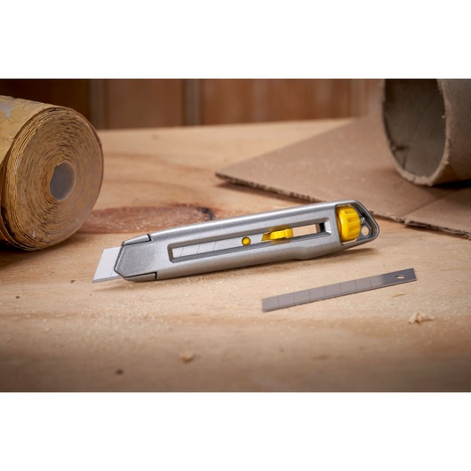 Photo of STANLEY 0-10-018 utility knife with yellow accents and extra blade on workbench, product category: Photography.