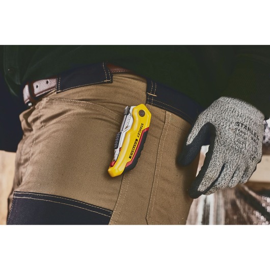 STANLEY 0-10-825 utility knife clipped to brown work pants, person wearing gloves.