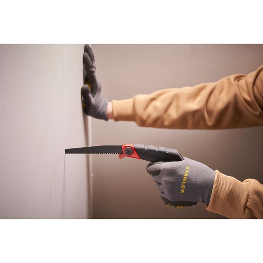 Stanley 0-20-108 folding saw, black and red handle, used to cut drywall, close-up photography.