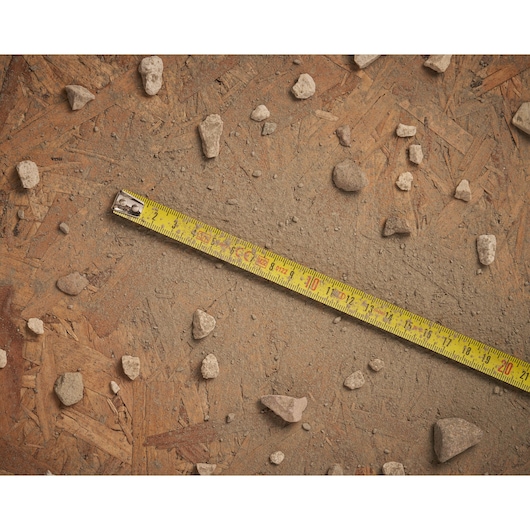 STANLEY 0-30-487 tape measure on dusty wooden surface with scattered rocks, top angle photography.