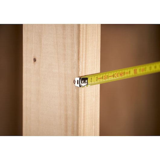 STANLEY 0-33-218 measuring tape photography, close-up of yellow tape measuring wooden beam.