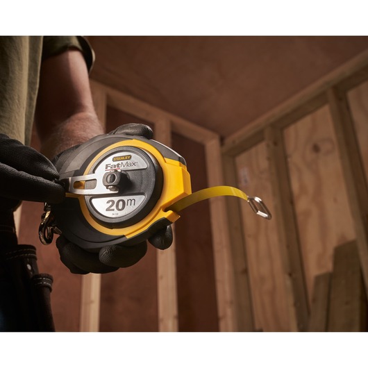 Photo of STANLEY 0-34-133 FatMax 20m tape measure held by gloved hand in construction setting.