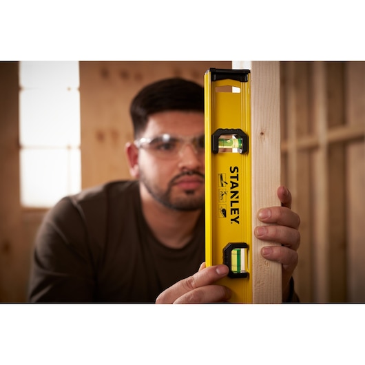 Photo of STANLEY 0-42-073 spirit level being used vertically against a wooden beam in a workshop.