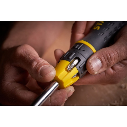 Close-up photo of STANLEY 0-68-010 multi-bit screwdriver handle showing bit storage and yellow grip.