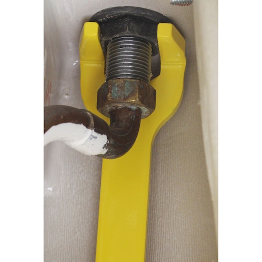 STANLEY 0-70-454 yellow pipe wrench in use on a metal plumbing fitting, close-up photo.