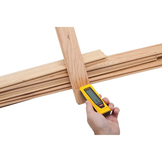 STANLEY 0-77-030 digital moisture meter held against wooden planks, front angle.