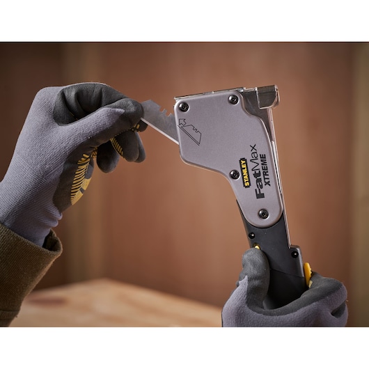 STANLEY 0-PHT350 staple gun held in gloved hands, loading a staple blade, indoor photography.