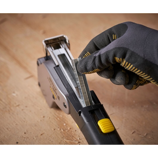 STANLEY 0-PHT350 hand tacker being loaded with staples, close-up view on wooden surface.