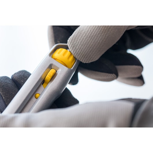 Photo of STANLEY 1-10-018 utility knife handle with yellow adjustment wheel in gloved hand.