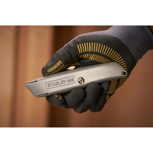 STANLEY 1-10-099 utility knife held in gloved hand, product close-up photography.