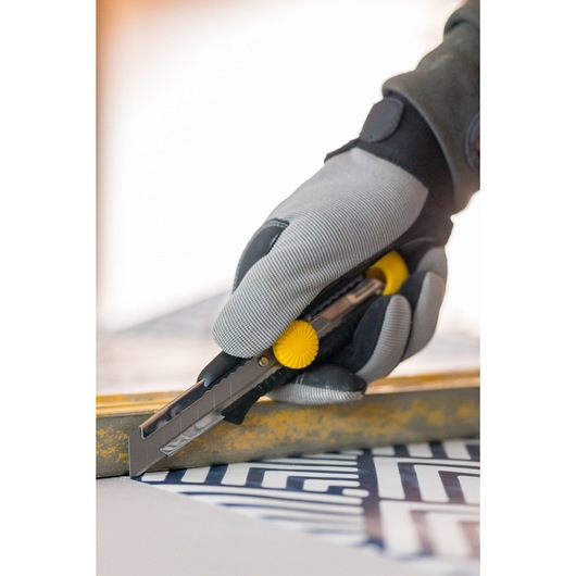 STANLEY 1-10-418 utility knife with yellow wheel, used by gloved hand to cut material.