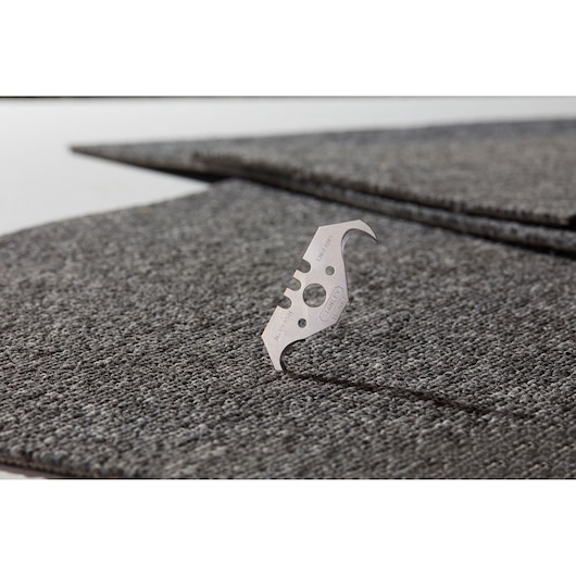 STANLEY 1-11-967 trapezoidal utility blade on gray carpet tiles, close-up, photography.