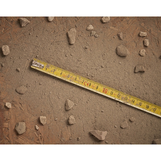 STANLEY 1-30-299 yellow measuring tape on dusty ground with scattered small rocks, top-down angle.