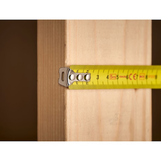 STANLEY 1-33-552 yellow tape measure measuring wooden plank, close-up photography.