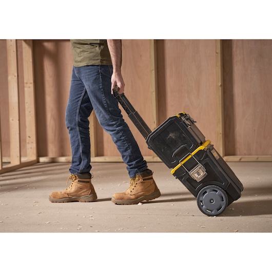 STANLEY 1-70-326 rolling tool box with yellow accents, shown being pulled by handle in workshop.