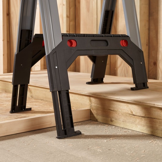 STANLEY 1-92-980 adjustable work platform legs with measurement markings, close-up side angle, on wooden floor.