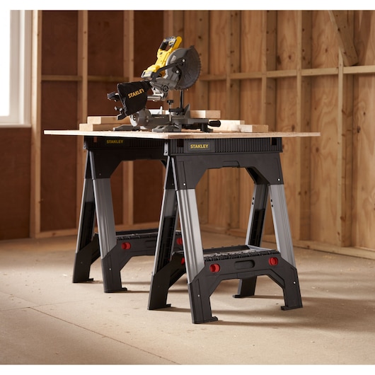 STANLEY 1-92-980 black and silver folding workbench used as a saw station in a workshop, shown at an angle.