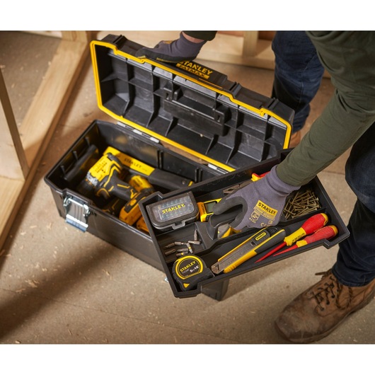 STANLEY 1-94-749 toolbox with assorted hand tools and accessories in workshop setting, top angle.