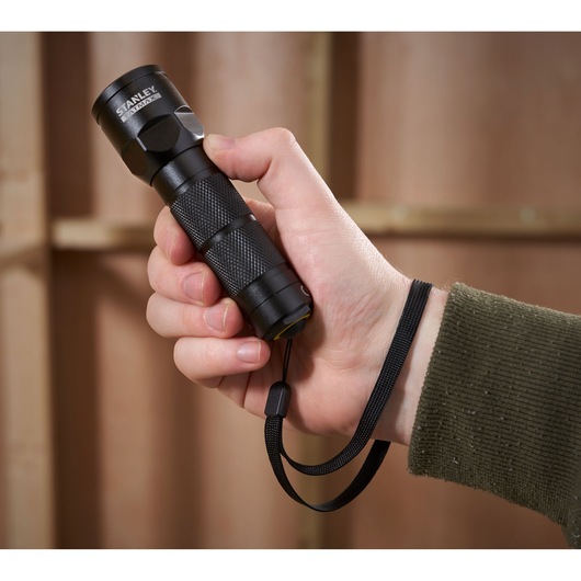 STANLEY 1-95-152 compact black flashlight with wrist strap, photography of product held in hand.