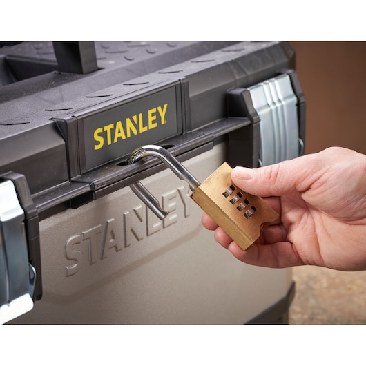 STANLEY 1-95-616 toolbox with hand unlocking a brass combination padlock, front angle.
