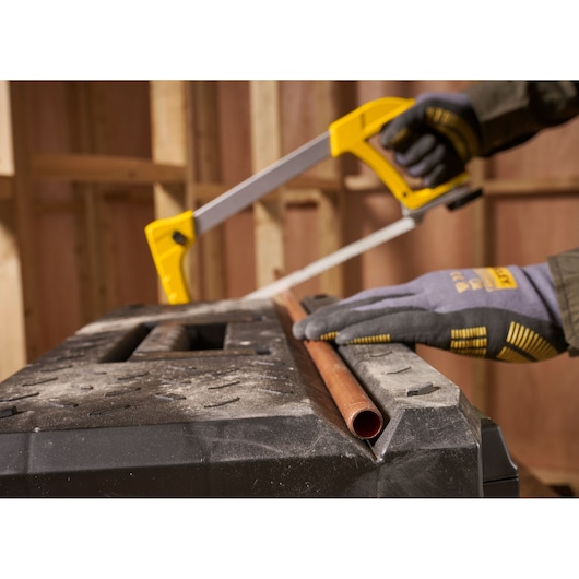STANLEY 1-95-618 hacksaw cutting copper pipe, close-up photo, gloved hand, workshop background