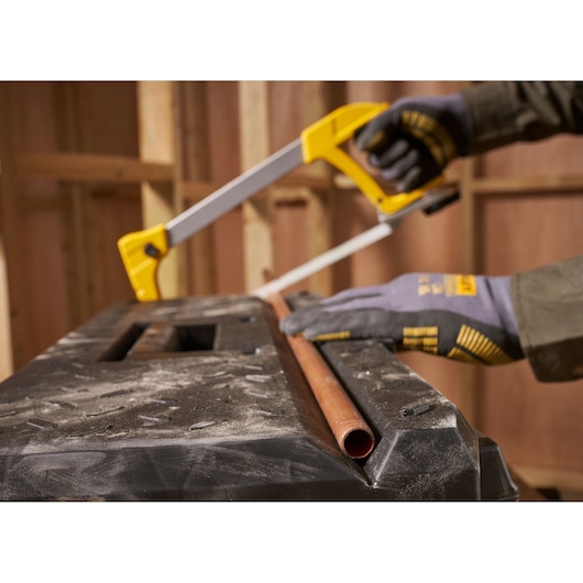 STANLEY 1-95-619 hacksaw cutting copper pipe on workbench, close-up angle, photography.