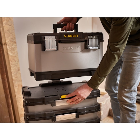 STANLEY 1-95-622 toolbox being placed on stackable storage boxes, shown in use indoors.