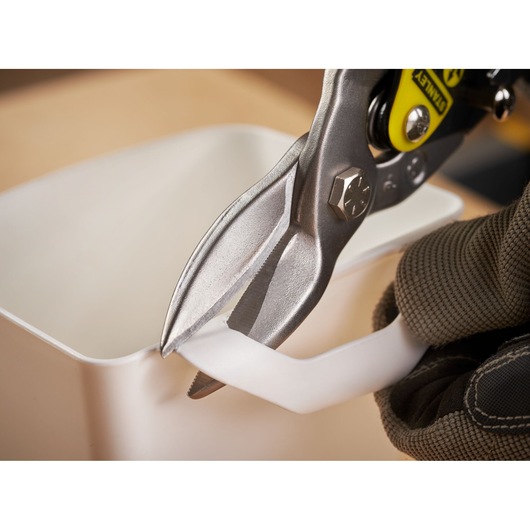 Photo of STANLEY 2-14-563 aviation snips cutting white plastic, close-up view.