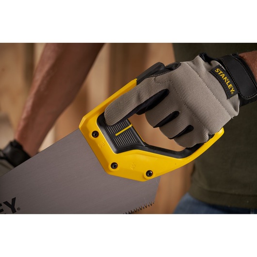 Photo of STANLEY 2-15-289 hand saw with yellow and black handle, gripped by a gloved hand, close-up view.