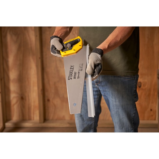 Photo of STANLEY 2-15-599 hand saw cutting metal, with yellow handle and gloves, product in use indoors.