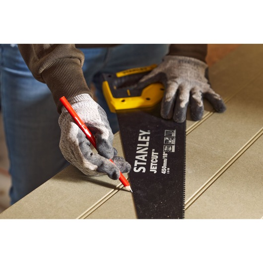 Photo of STANLEY 2-20-180 hand saw held by gloved hands, marking a line on wood with a red pencil.