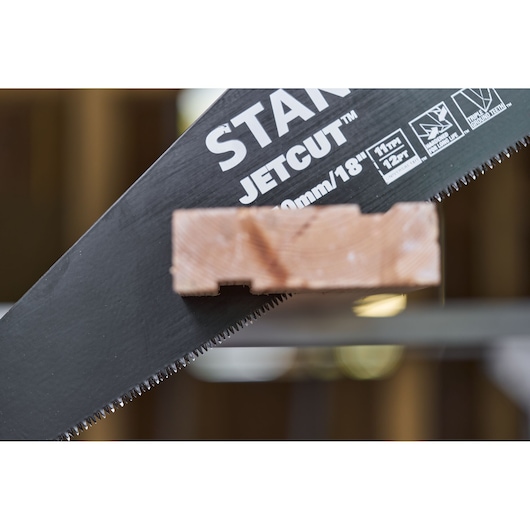 STANLEY 2-20-180 hand saw blade close-up cutting wood, showing sharp teeth and product branding.