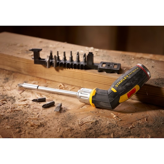 STANLEY FMHT0-62691 ratcheting screwdriver with black and yellow handle, bit holder and bits on wood.