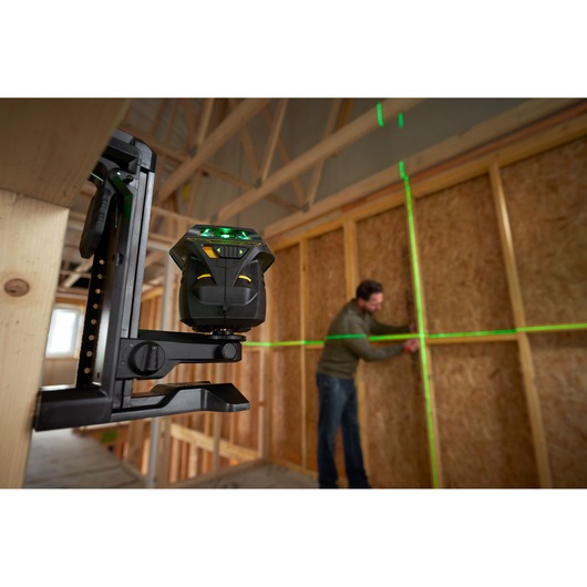 STANLEY FMHT1-77356 laser level projecting green lines on wall in construction site, side angle view.