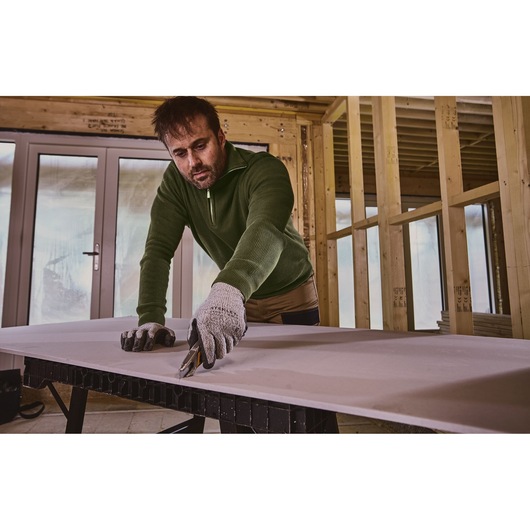 Stanley FMHT10592-0 utility knife used to cut drywall on a workbench in a construction interior.