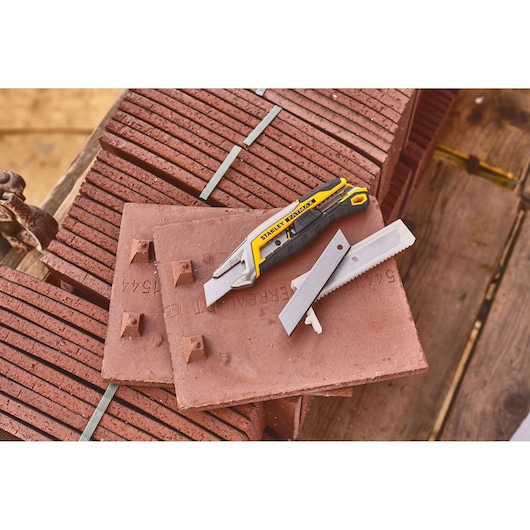STANLEY FMHT10594-0 utility knife and replacement blades on red construction tiles, photography at jobsite.