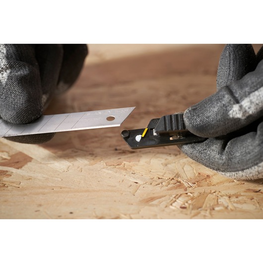 STANLEY FMHT10594-0 utility knife with segmented blade, close-up in use on wooden surface.