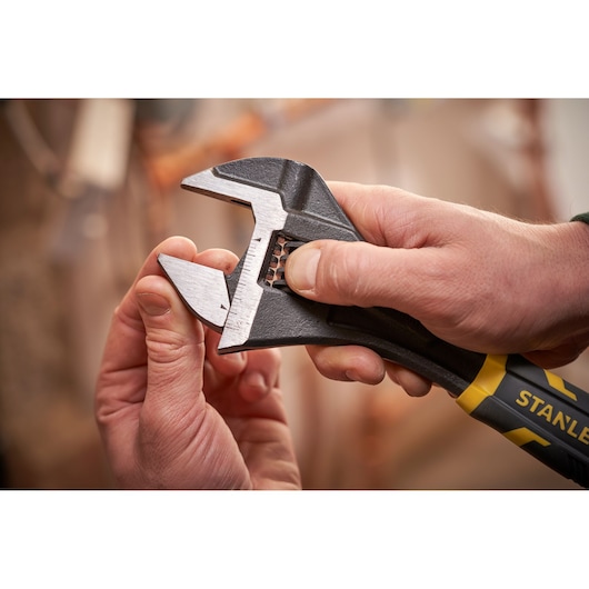 Close-up photo of STANLEY FMHT13128-0 adjustable wrench with black and yellow handle being adjusted by hand.