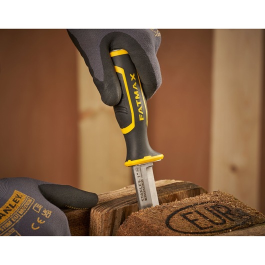 STANLEY FMHT16693-0 chisel with black and yellow FATMAX handle in use on wood surface, close-up.