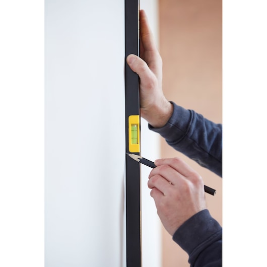 STANLEY FMHT42559-1 spirit level in use against a wall, person marking with pencil.