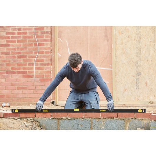 STANLEY FMHT42561-1 spirit level used by builder on brick wall construction site.