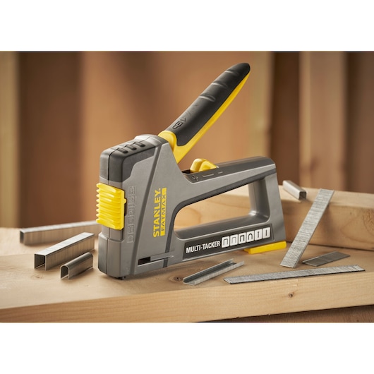 STANLEY FMHT6-70868 Multi-Tacker stapler in grey and yellow with staples on wooden surface.