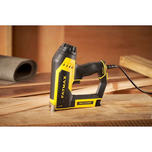 STANLEY FMHT6-75934 electric multi-tacker, black and yellow, side angle, on wooden workspace.