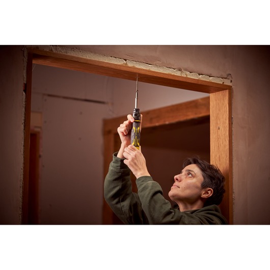 STANLEY FMHT62692-0 screwdriver held upright during door frame installation, yellow and black handle visible.