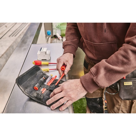Photo of STANLEY FMHT66426-0 insulated screwdriver set in black roll-up pouch on metal table.