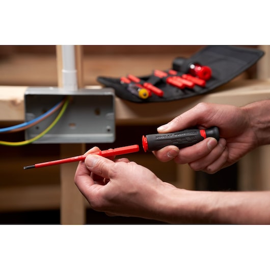 STANLEY FMHT66426-0 insulated screwdriver kit in use, featuring red interchangeable bits and pouch.