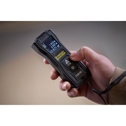 STANLEY FMHT77165-0 laser distance measurer held in hand, close-up view.