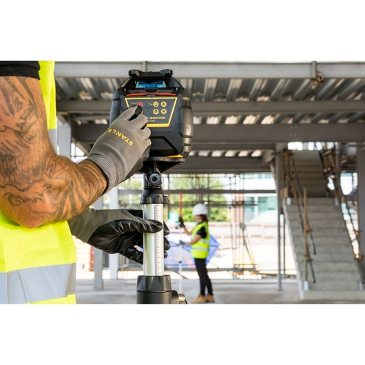 STANLEY FMHT77449-1 rotary laser level on tripod, used at a construction site.