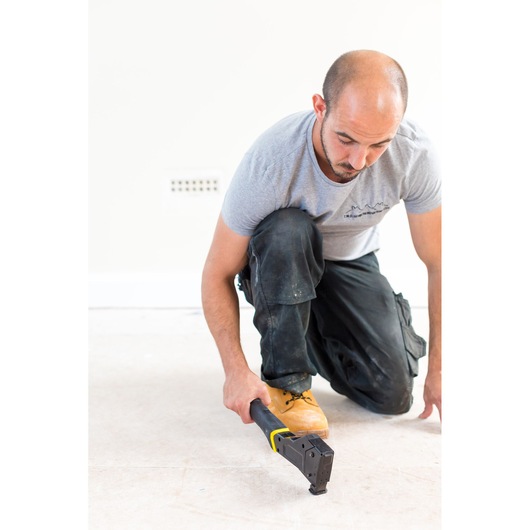 STANLEY FMHT81394-9 manual flooring stapler in use, person kneeling on unfinished floor.
