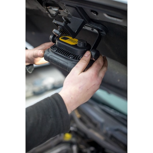 STANLEY FMHT81507-1 work light mounted under car hood in use, hands adjusting black and yellow light.